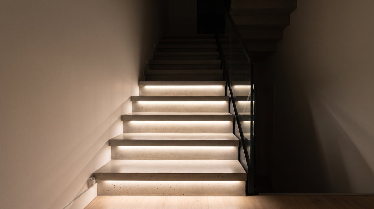 Treppe bei Nacht mit Lauflicht-Effekt: die unteren Stufen sind durch bewegungsgesteuerte warmweiße LED-Streifen beleuchtet, die oberen noch dunkel